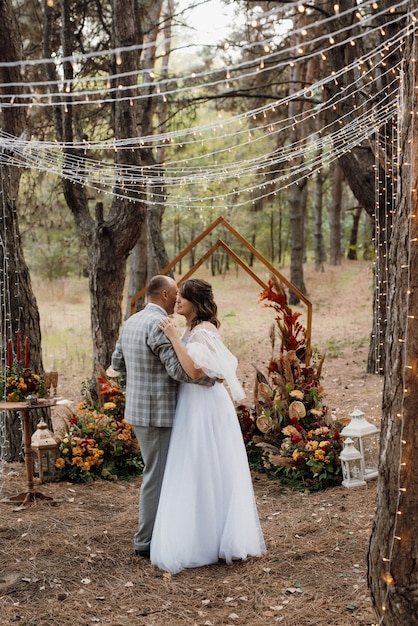 Man en vrouw raakten verloofd in het herfstbos tijdens een bruiloft versierde ceremonie