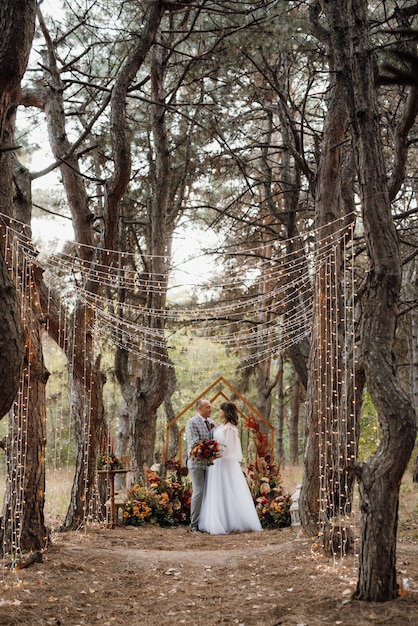 Man en vrouw raakten verloofd in het herfstbos tijdens een bruiloft versierde ceremonie