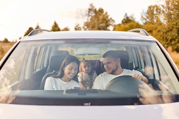 Man en vrouw rijden in de auto met hun dochtertje stoppen voor pauze vrouw die telefoon laat zien aan echtgenoot familie die positieve emoties uitdrukt Vakantietoerisme