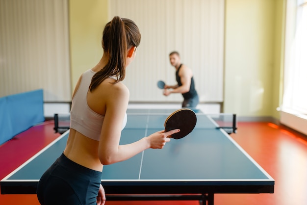 Man en vrouw spelen pingpong binnenshuis