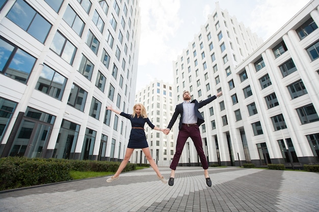 Man en vrouw springen op de achtergrond van het gebouw van het zakencentrum.