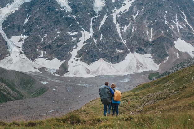 Man en vrouw staan en knuffelen op de top van de berg