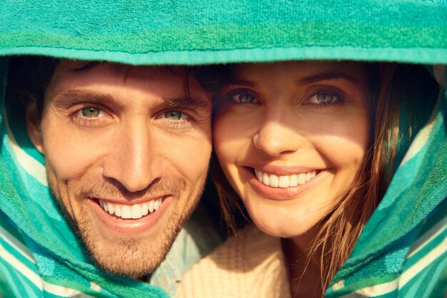 Man en vrouw strand handdoek voor bescherming of portret samen voor weekend binding of omhelzen Gelukkige paar gezicht en knuffelen voor warm comfort voor het weer of liefdesreis voor avontuur buiten of plezier