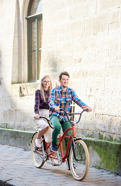 man en vrouw tandem fietsen langs stadsstraat