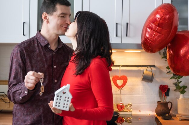 Man en vrouw verliefd date thuis in keuken met sleutels van huis Valentijnsdag gelukkig paar liefdesverhaal Liefdesnest hypotheek verhuizing aankoop onroerend goed huisvesting voor jong gezin