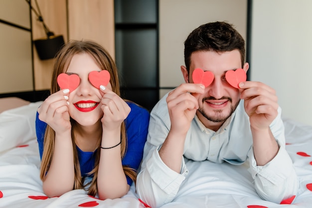 Man en vrouw verliefd in bed met hartvormen