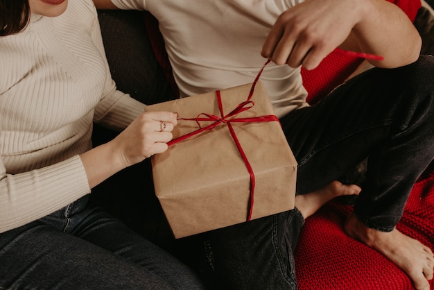 Man en vrouw verliefde paar openen geschenkdozen, maken een boog los bij de kerstboom