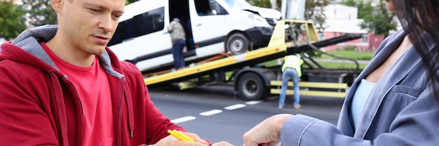 Foto man en vrouw vullen papierwerk in na auto-ongeluk. verzekeringsagent concept