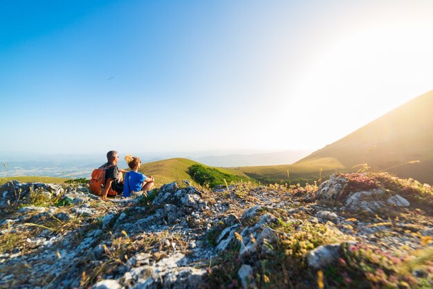 Man en vrouw wandelen in de bergen van de regio Umbrië, Monte Cucco, Appennino, Italië. Paar kijken naar zonsondergang samen op de bergtop. Zomer buitenactiviteit.