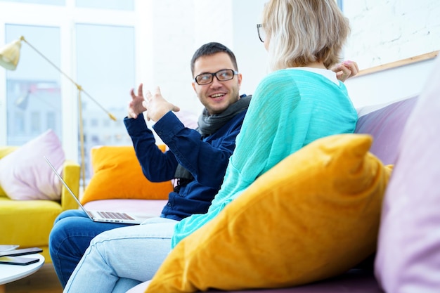 Man en vrouw zitten op de bank te kletsen en een desktopcomputer te gebruiken