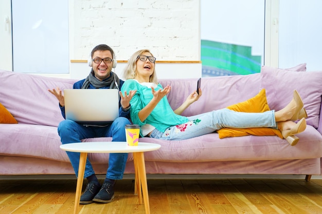 Man en vrouw zitten op de bank te kletsen en een smartphone-desktopcomputer te gebruiken