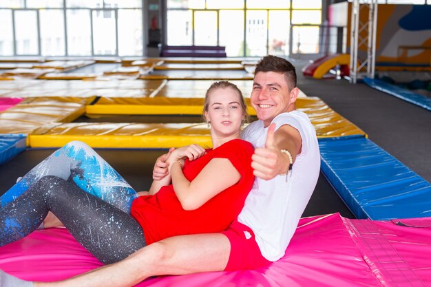 Man en vrouw zitten samen op een trampoline binnenshuis.