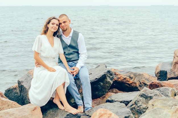 man en vrouw zittend op de rotsen bij de zee