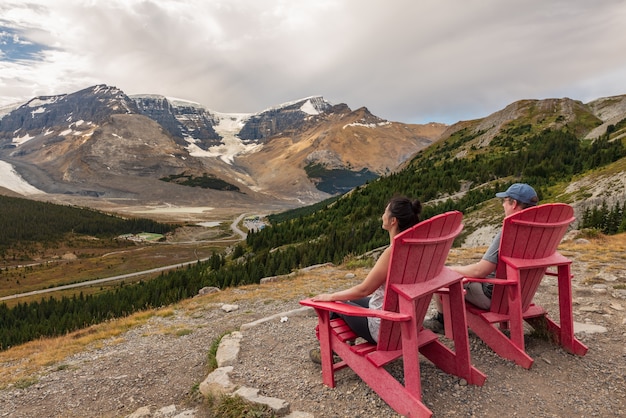 Man en vrouw zittend op rode stoelen die het uitzicht van Wilcox trail in Jasper National Park, Alberta, Canada in zich opnemen.