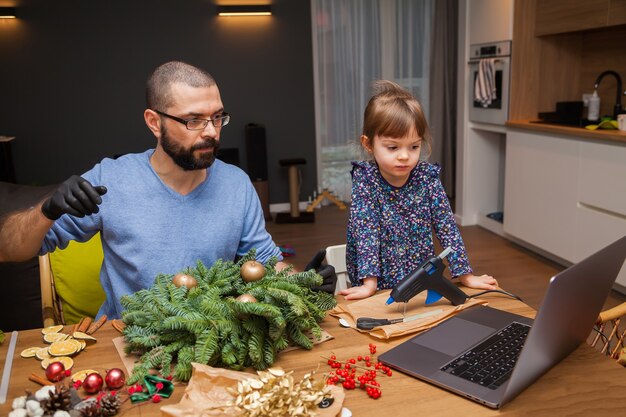 Man en zijn dochtertje leren een kerstkrans te versieren les online kijken