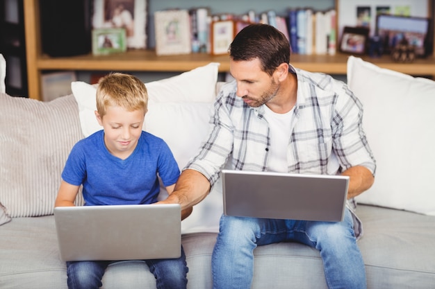 Man en zoon die op laptop werkt