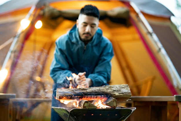 A man enjoying a bonfire in front of tent