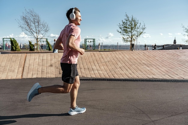 Man enjoying a brisk run with headphones staying fit in an urban park setting