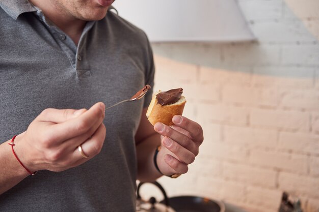 チャバタスライスにナッツバターを塗るチョコレートペーストを食べるのを楽しんでいる男