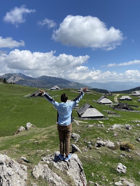 男は山の高山の村の景色を楽しんでいます。ヴェリカ・プラニナ。大きな牧草地の高原。スロベニア