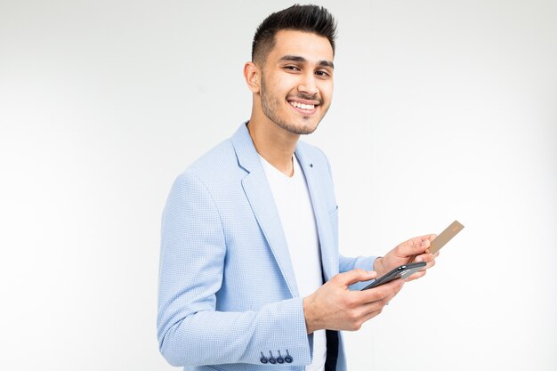 A man enters data with a credit card into a mobile phone to make a purchase via the Internet on a white background