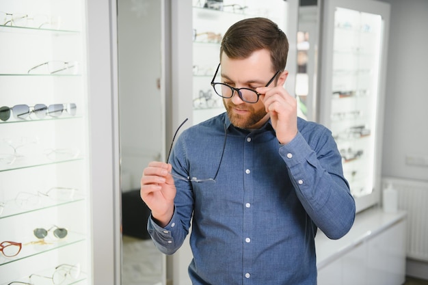 Photo man evaluating quality of glasses in optical shop