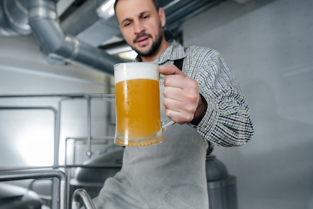 A man examines a glass of beer in a brewery.