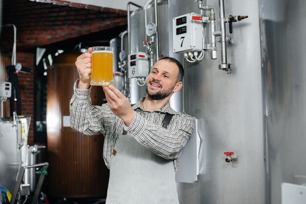 Foto un uomo esamina un bicchiere di birra in una fabbrica di birra.