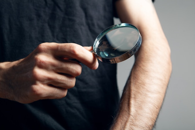 A man examines a hand with a magnifying glass