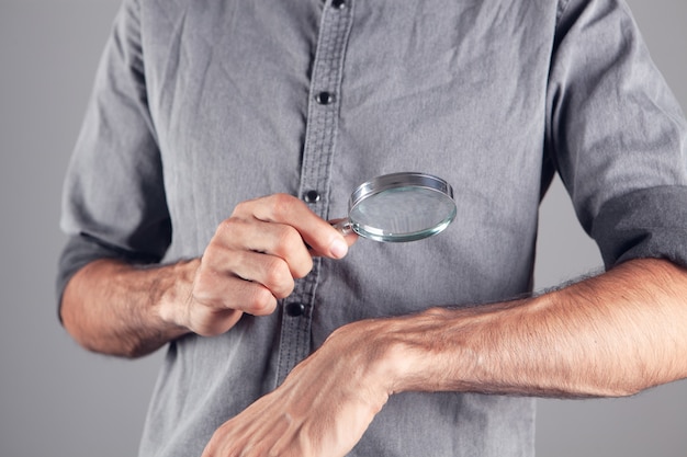 A man examines a hand with a magnifying glass