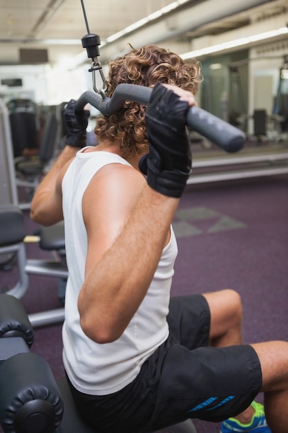 Photo man exercising on a lat machine in gym