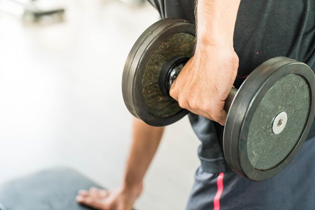 Photo man exercising with dumbbell at gym