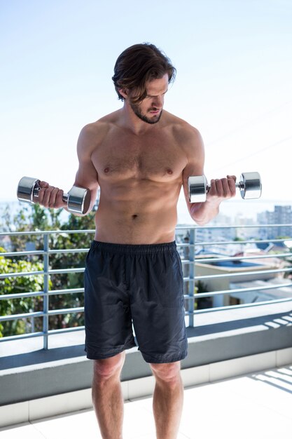 Man exercising with dumbbells in balcony