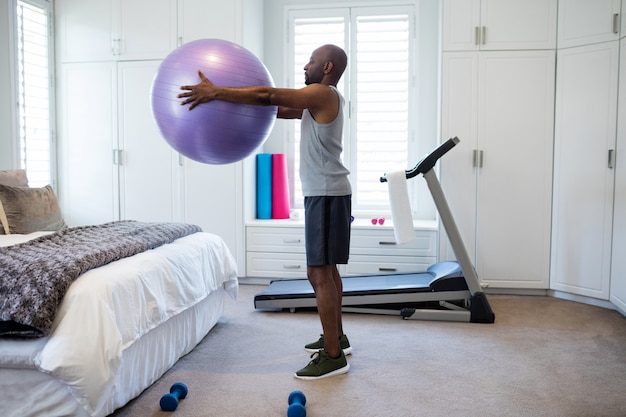 Man exercising with fitness ball in bedroom