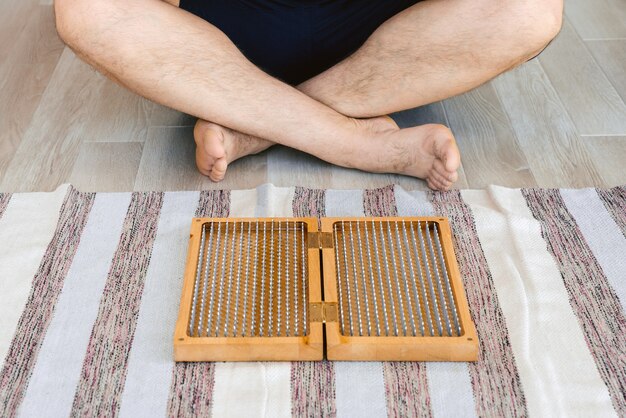 Man exercising yoga meditating sitting hands joined on the floor near sadhu board