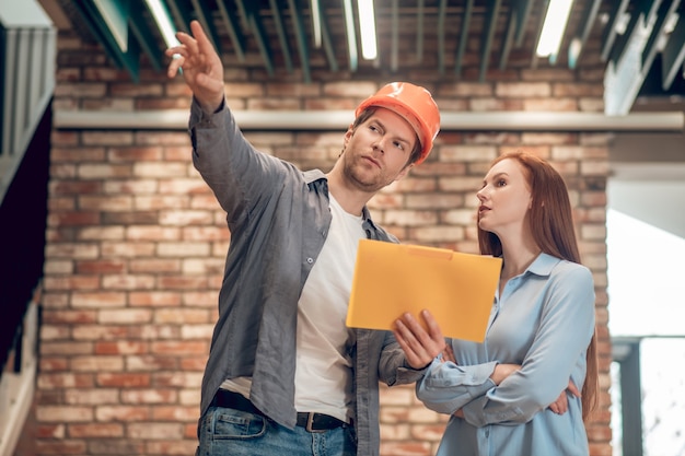 Man explaining showing construction plan to woman