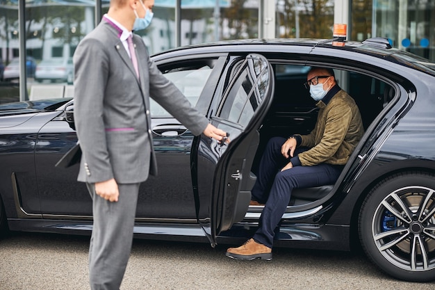 Man in eyeglasses getting out of the elite taxi