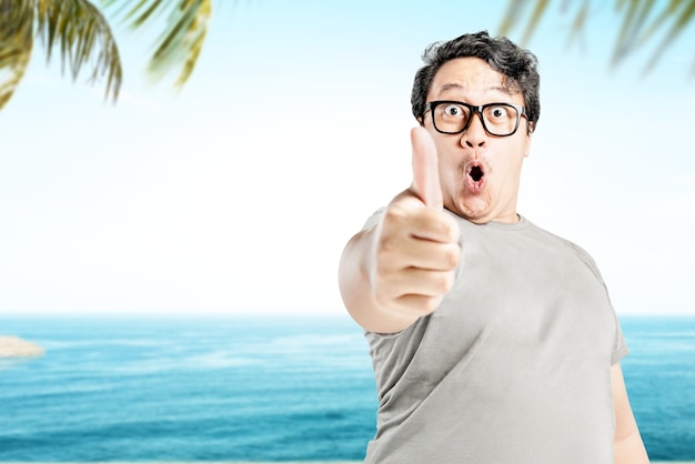 Man in eyeglasses showing thumb up on the beach