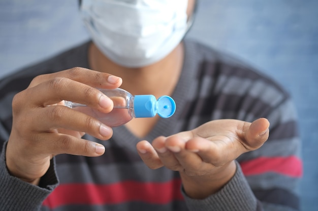 Man in face mask using sanitizer liquid for preventing corona virus