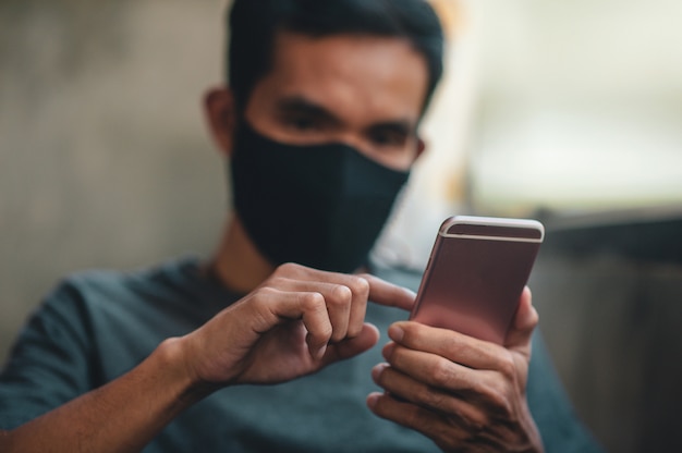 Man in a face mask using a smartphone