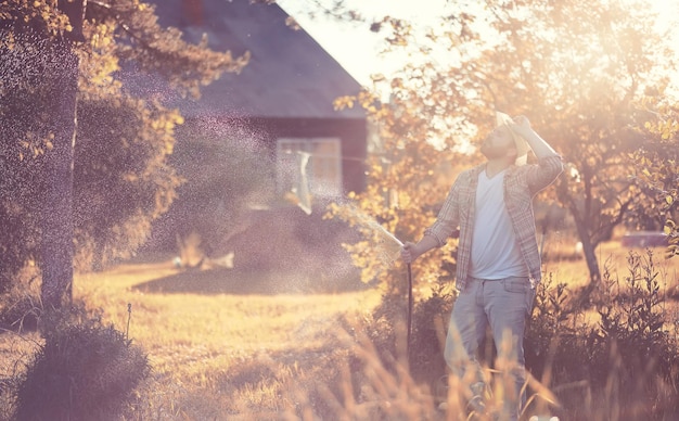 Man farmer watering a vegetable garden in the evening at sunset