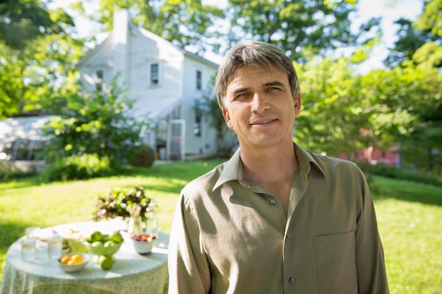 A man in a farmhouse garden, beside a round table with fresh lemonade drinks.