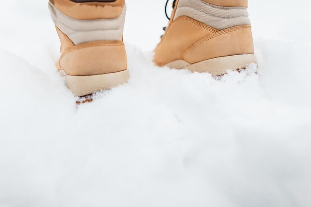 man in fashion winter beige boots walks in the snow on a winter day, close-up. Copy space for text