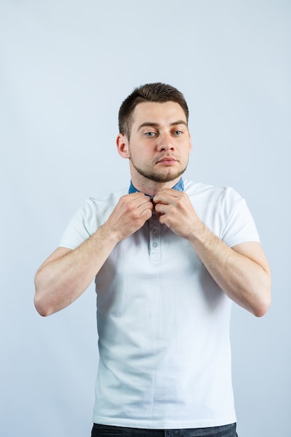 A man fastens a button on his white polo