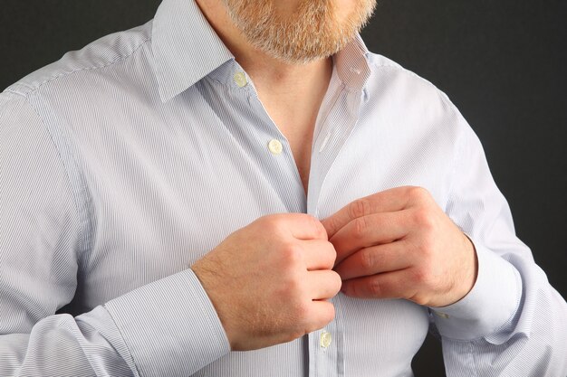 man fastens buttons on his shirt