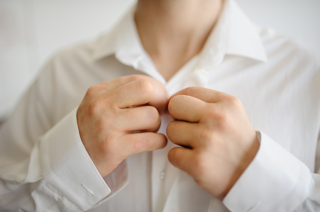 A man fastens buttons on a shirt on a collar. Close-up.