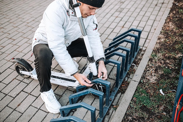 男が自転車スクーターのロック盗難に電動スクーターを固定する