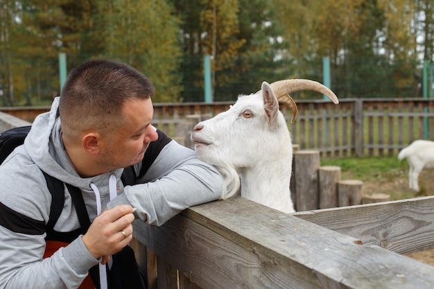 動物園のヤギにリンゴを食べている男