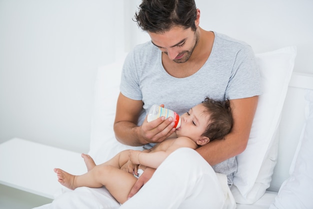 Man feeding milk to baby girl