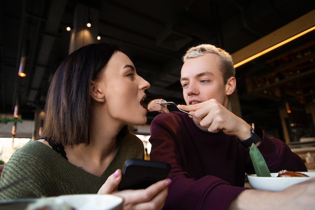 Man feeds woman in cafe happy couple spends time in restaurant